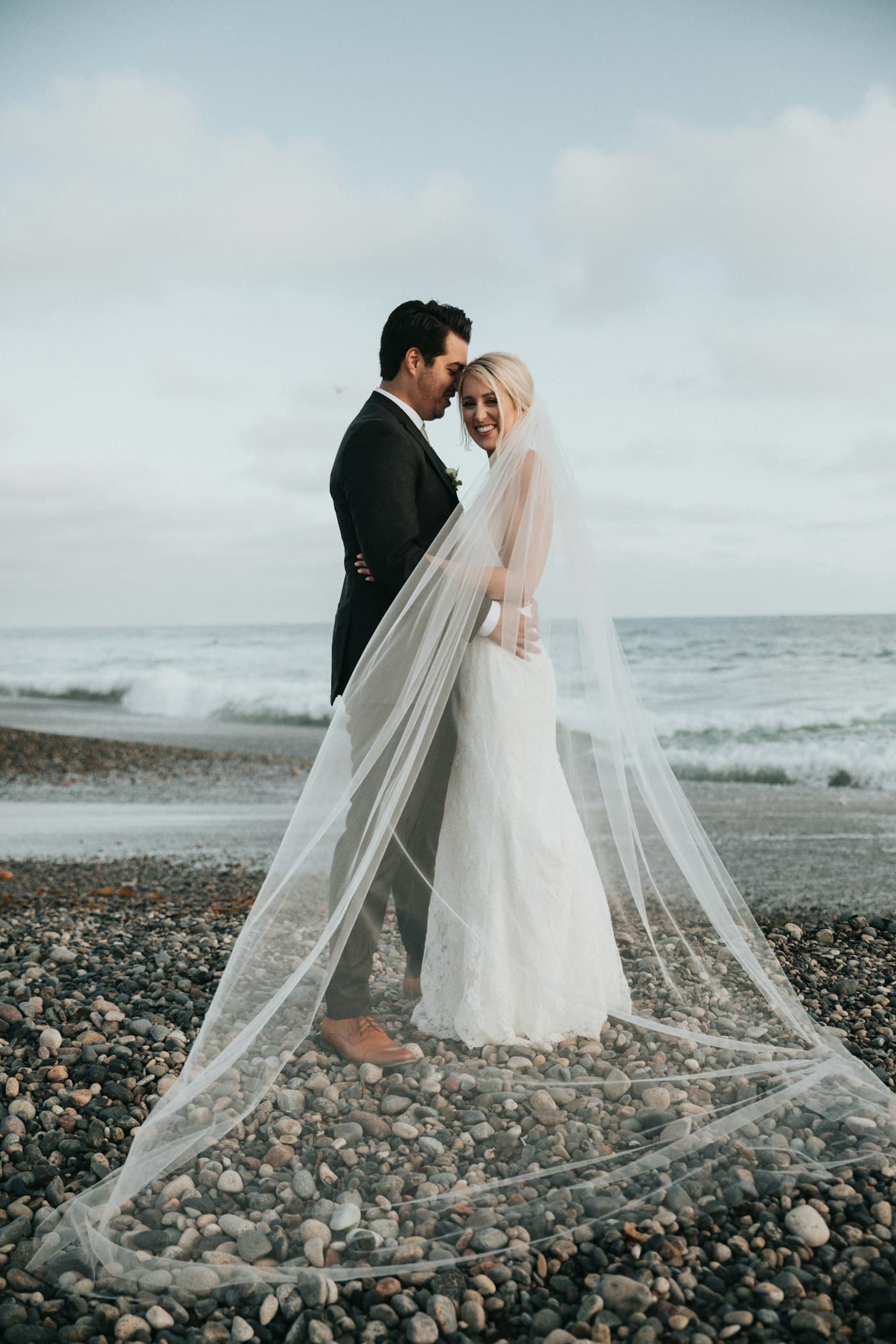 A couple on the beach, his forehead against hers.